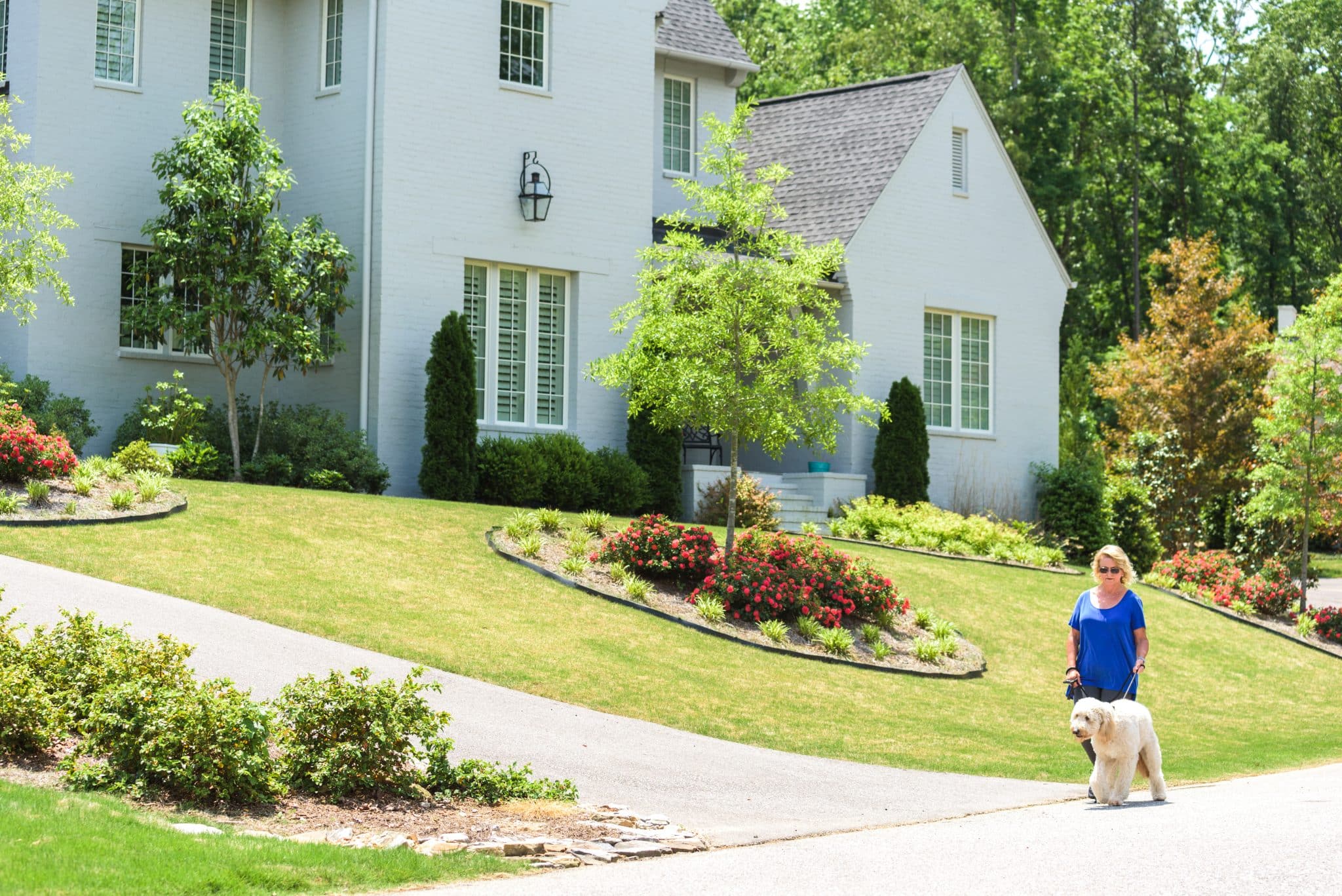 The front of a house with a garden bed, well-manicured lawn, and trimmed bushes